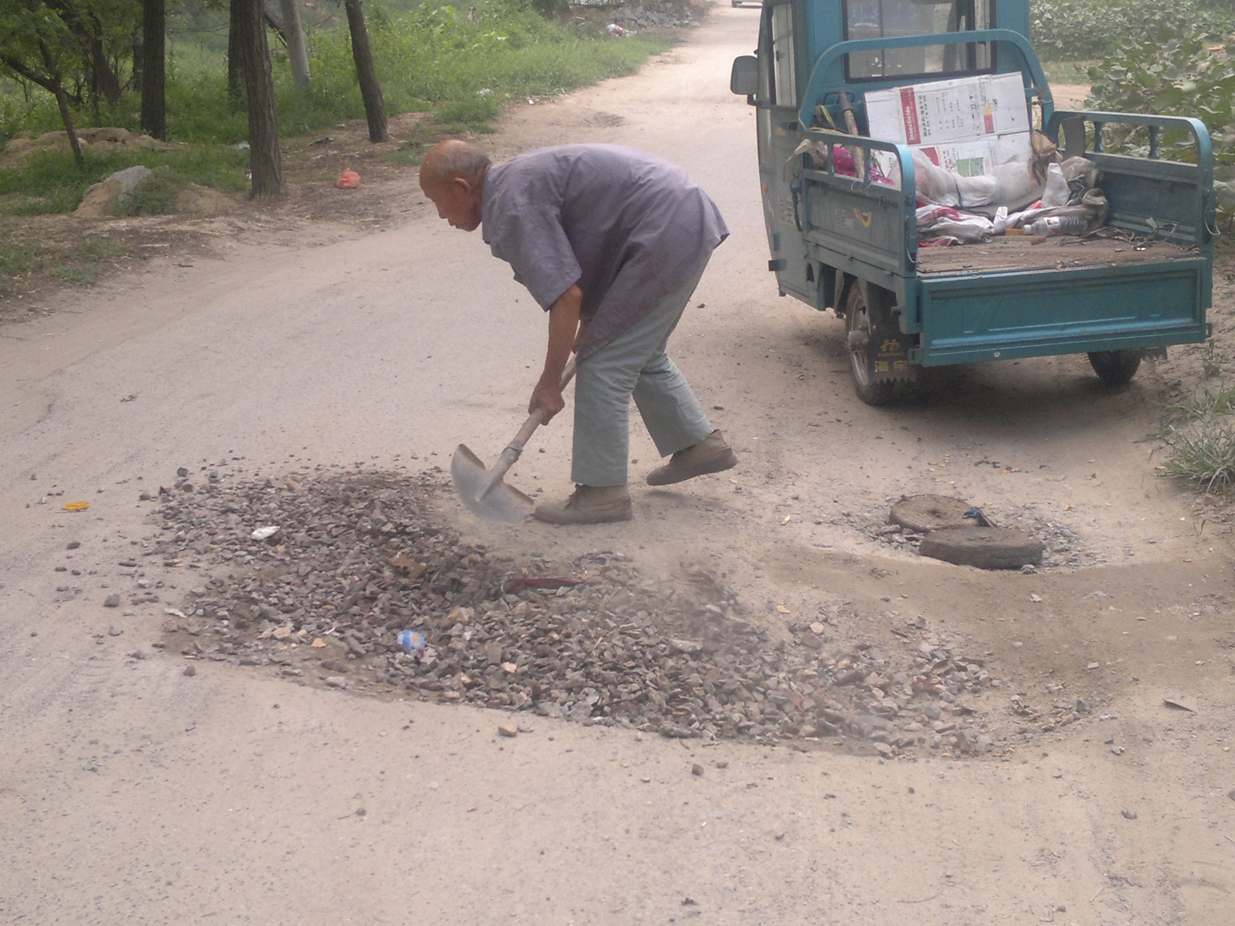 王树金老人正在用捡来的废弃石渣修补路面1.jpg